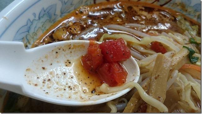 ざく切りのトマトが入った濃厚なラーメンの写真